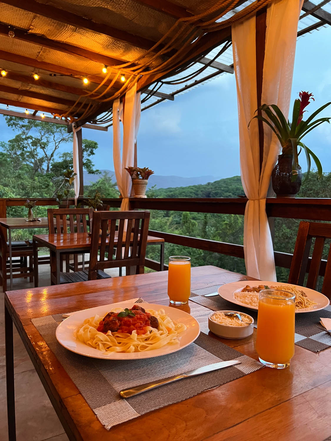 Mesa do restaurante com massa e suco, com vista para as montanhas